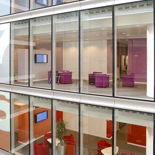 Corporate Digital Signage | An image showing digital signage on different floors within an office space through floor-to-ceiling windows